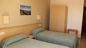 a hotel room with two beds and a cabinet at Hostal Sa Prensa in Ciutadella