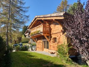a log cabin with a balcony in a yard at BARMADZA Mazots de Charme in Demi-Quartier
