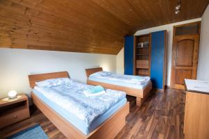 two beds in a room with wooden walls and wooden floors at Holiday apartment Pika in Bovec