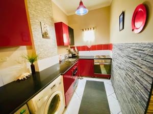 Desert Pearl Apartment في الغردقة: مطبخ مع دواليب حمراء وغسالة ملابس