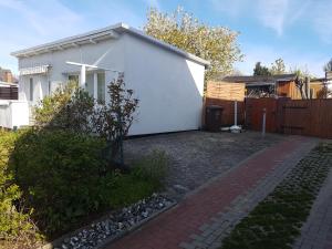 une maison blanche avec une clôture et une allée en briques dans l'établissement Ferienwohnung in Bodden & Ostsee nähe, à Sagard