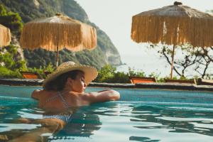 a woman in a hat sitting in a swimming pool at Hotel Albatros in Ischia