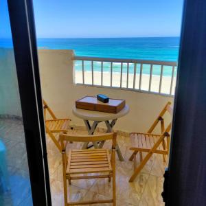 una mesa y sillas en un balcón con vistas al océano en Flores casas de playa en Alexandría