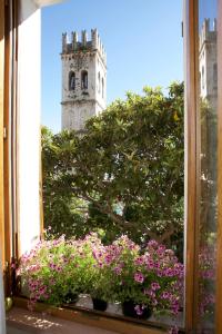 a window with flowers and a clock tower in the background at LE DIMORE ARCANGELO Maria in Assisi