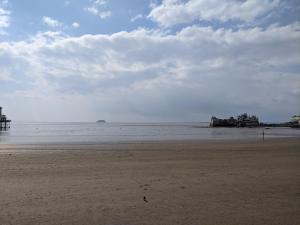 a sandy beach with a pier in the water at Parasol Weston Guest House in Weston-super-Mare