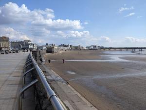 a beach with people walking on the sand and a pier at Parasol Weston Guest House in Weston-super-Mare