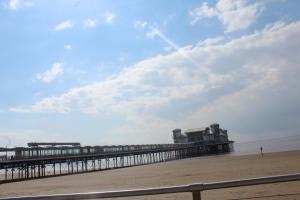a pier on the beach with a person walking on the beach at Parasol Weston Guest House in Weston-super-Mare