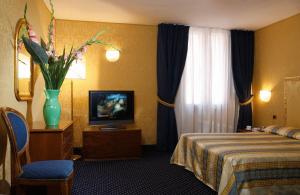 a hotel room with a bed and a vase of flowers at Hotel Castello in Venice