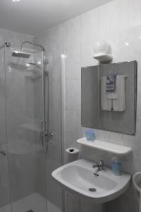 y baño blanco con lavabo y ducha. en Pensión Residencia Casa Teresa, en Vista Alegre