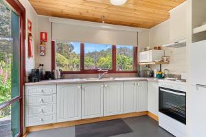 una cocina con armarios blancos y una ventana en Hamlet Downs Country Accommodation en Fentonbury