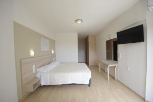 a bedroom with a bed and a flat screen tv at Evia Riviera Resort in Amarynthos
