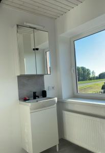 een witte badkamer met een wastafel en een raam bij Ferienwohnung Spieker in Hamburg in Hamburg