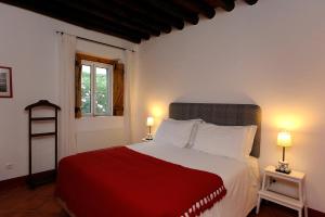 um quarto com uma cama vermelha e branca com 2 candeeiros em Casas de Juromenha em Jurumenha
