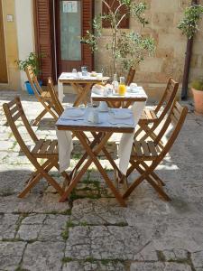 una mesa de madera con 2 sillas y una mesa con comida. en B&B DIMORA PALMIERI, en Monopoli