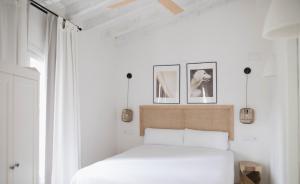 a bedroom with a white bed with three pictures on the wall at Quinta la Sal in Jávea