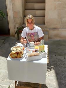 a woman sitting at a table with a plate of food at B&B DIMORA PALMIERI in Monopoli