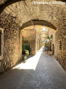 un callejón de piedra con un arco en un edificio en U Carùggiu, en Villanova dʼAlbenga