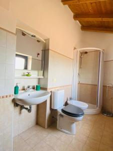 Un baño con lavabo, inodoro y espejo. en Casa Nalu', en Taormina