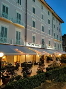 モンテカティーニ・テルメにあるグランド ホテル ニッツァ エ スイスの中庭に日よけ付きの白い大きな建物