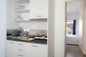 a kitchen with white cabinets and a plate of fruit on the counter at Blue Senses Apartments in Sarti