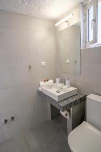 a white bathroom with a sink and a toilet at Blue Senses Apartments in Sarti