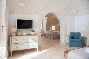 uma sala de estar com uma televisão e uma cadeira azul em Chiancole - Trulli Experience em Alberobello