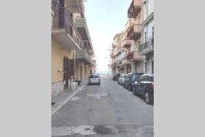 una calle vacía con coches estacionados a los lados de los edificios en Apartment Miriade, en Balestrate