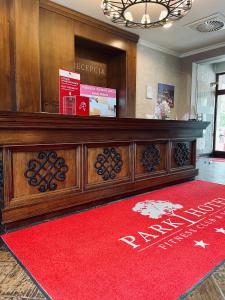 un vestíbulo con un gran escritorio de madera con una alfombra roja en Park Hotel & Fitness Club Rzeszów, en Rzeszów