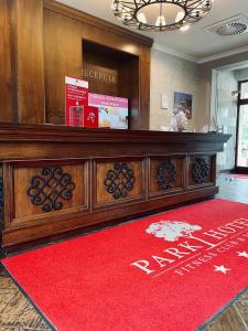 a lobby with a large wooden desk with a red rug at Park Hotel & Fitness Club Rzeszów in Rzeszów