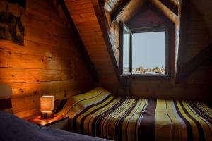 1 dormitorio en una cabaña de madera con cama y ventana en Sojenica Ivona en Ulcinj