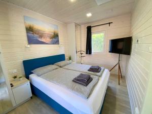 a bedroom with a bed and a flat screen tv at Naturhaus Wassermann mit Boxspringbetten in ruhiger Lage, Meernähe in Wunstorf