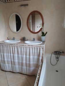 W łazience znajdują się 2 umywalki, wanna i lustra. w obiekcie Villa Maryne w mieście Andernos-les-Bains