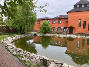 a pond in front of a brick building at Гостинний маєток in Myla