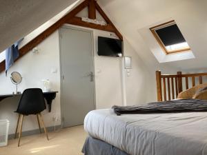 a bedroom with a bed and a desk and a tv at Hôtel de la Mer in Pléneuf-Val-André