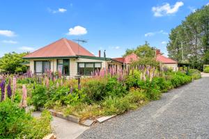 a house with a garden of flowers in front of it at Hamlet Downs Country Accommodation in Fentonbury