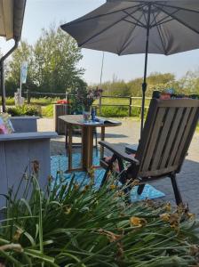 卡蘭茨奧赫的住宿－B&B Buiten Gewoon Callantsoog，桌子和带雨伞的椅子