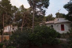 a white house with a red window and trees at Quinta la Sal in Jávea
