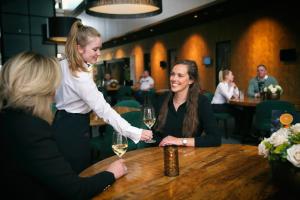 zwei Frauen sitzen an einem Tisch mit Weingläsern in der Unterkunft Van der Valk Hotel Rotterdam - Blijdorp in Rotterdam