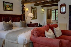 een slaapkamer met een groot bed en een rode bank bij The Moonraker Hotel in Bradford on Avon