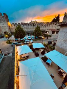 un patio con sombrillas azules frente a un castillo en Locanda Lo Scudo, en Soave