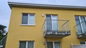 a yellow building with a balcony at Seenadel in Gelbensande