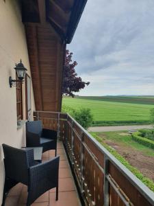 a balcony with chairs and a view of a field at Ferienwohnung im Schwarzwaldhaus in Behla