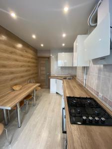 cocina con armarios blancos y encimera de madera en Квартира с раздельными комнатами, левый берег, пр Правды, Ул Калиновая, en Dnipro