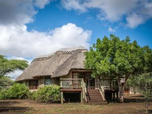 een huis met een rieten dak en een veranda bij Rhino River Lodge in Manyoni Private Game Reserve