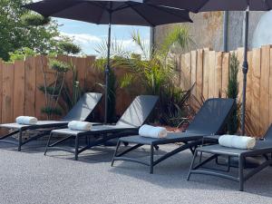 3 chaises longues et un parasol sur la terrasse dans l'établissement Logis Au Vieux Morvan, à Château-Chinon