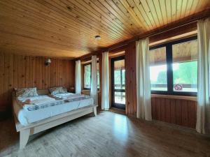 a bedroom with a bed in a wooden room with windows at Dom Wakacyjny z ogromnym ogrodem in Witaszyn