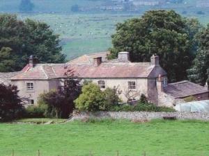 an old house on top of a green field at Temple Farm House in Aysgarth