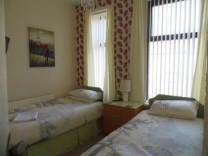 two twin beds in a room with two windows at The Pembroke in Blackpool