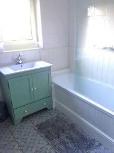 a bathroom with a blue sink and a tub at Riverwood Cottage Stanhope in Stanhope