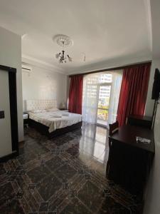 um quarto com uma cama, uma secretária e uma janela em Hotel Eurasia em Batumi